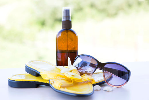 an amber dropper bottle, sunglasses, and a pair of sandals